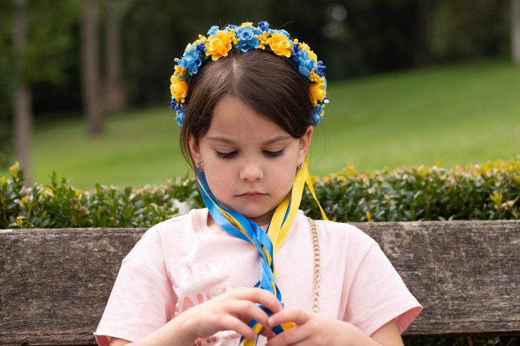 Dziewczynka z wiankiem na głowie z kwiatów w kolorze żółto niebieskim