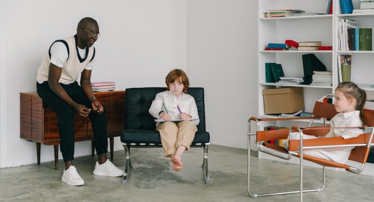 Grafika przedstawiająca mężczyznę rozmawiającego z dziewczynką i chłopcem w pokoju.