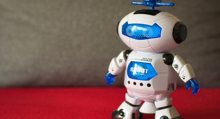 Robot - zabawka stojacy na dywanie w kolorze czerwonym.